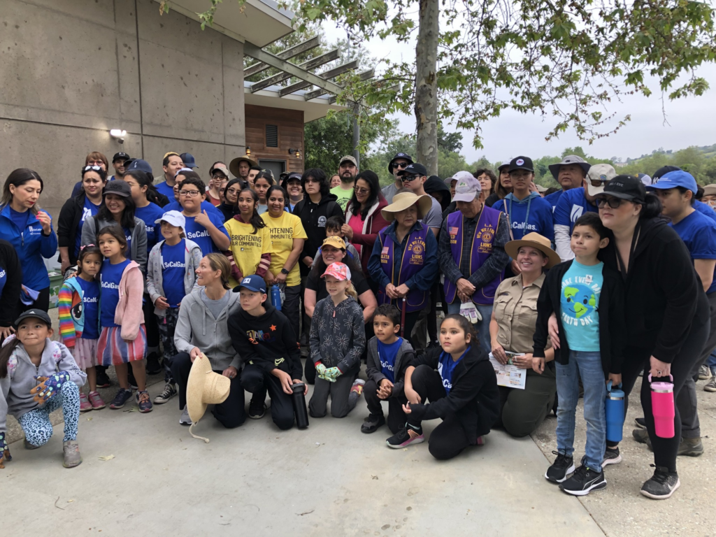 A group of volunteers organized for a photo with a building and tree in the background.