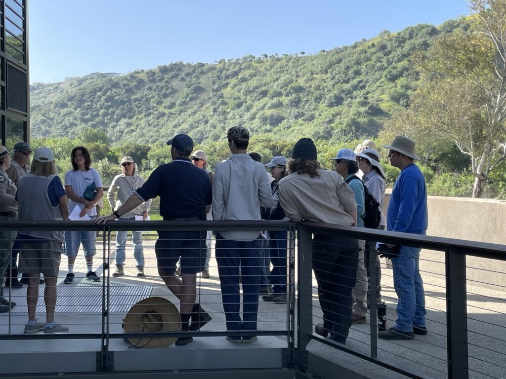 People gathered on a deck listening to a presentation.