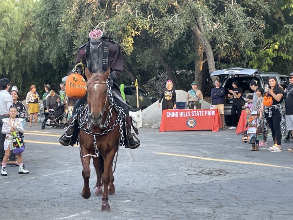 An image of the headless Horseman on a paved lot with bystanders.