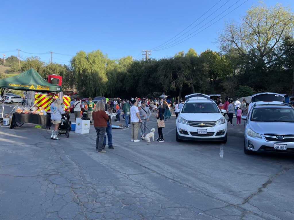A photograph of people at a Halloween party outdoors in a parking lot.
